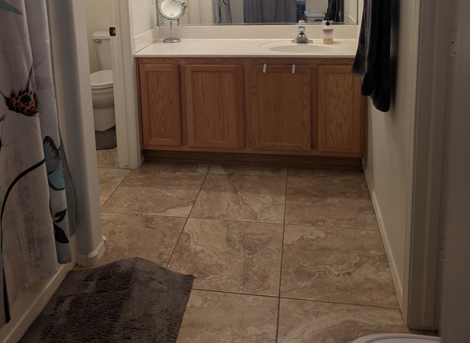 Primary bathroom with long vanity, tile floor, and separate toilet room