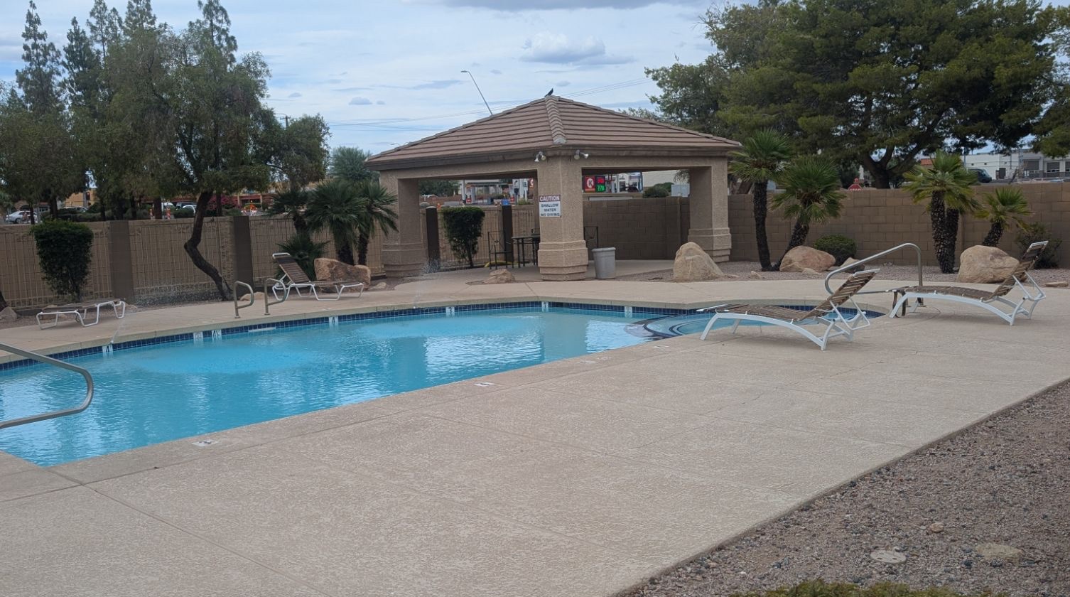 Community pool with lounge chairs and a shaded ramada